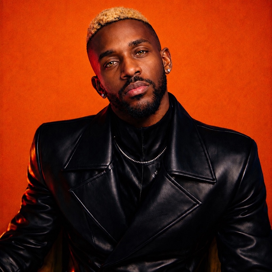 Marc Tovin in a black leather coat against a burnt-orange backdrop